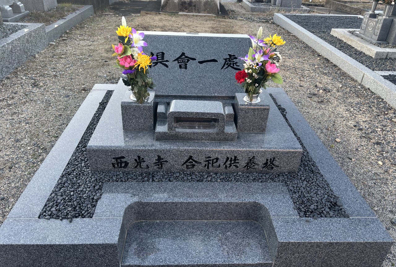 西光寺の合祀供養塔。「倶會一處」と刻まれた石碑の両脇に花が供えられている